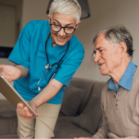Frau zeigt älterem Mann etwas auf einem Tablet - Dienstplan Pflege