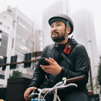 Lieferdienst Mitarbeiter mit Handy in der Hand auf dem dem Fahrrad - Dienstplan Lieferdienst