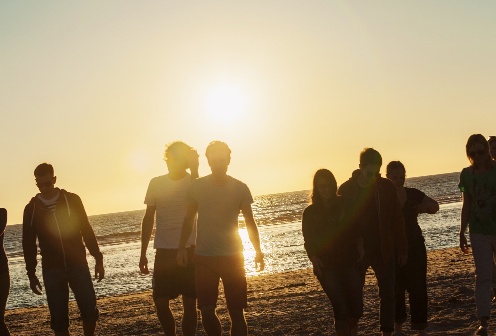 Gruppe von Menschen am Strand bei Sonnenuntergang